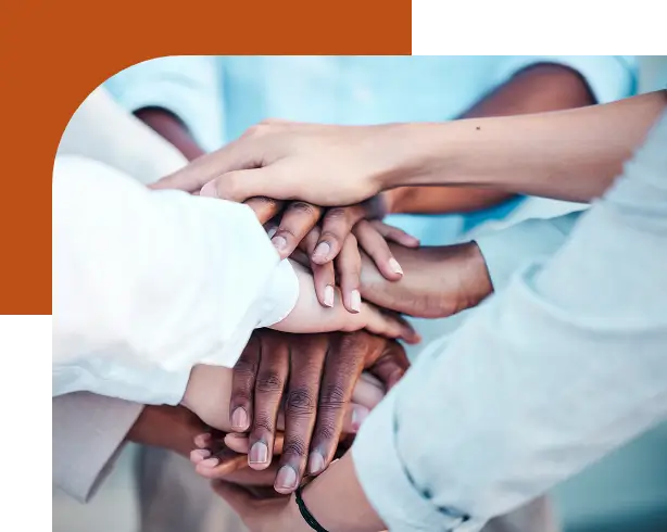 A number of hands from a diverse group of people, stacked on top of each other